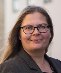 A woman wearing a suit and glasses is standing on a street. AI-genereret indhold
