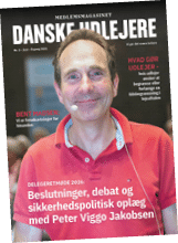 A person wearing a red polo shirt and a headset microphone is smiling on the cover of a Danish magazine titled “Danske Udlejere" with text about a 2026 delegate meeting and discussions on safety policy. Beskrivelse genereret af AI